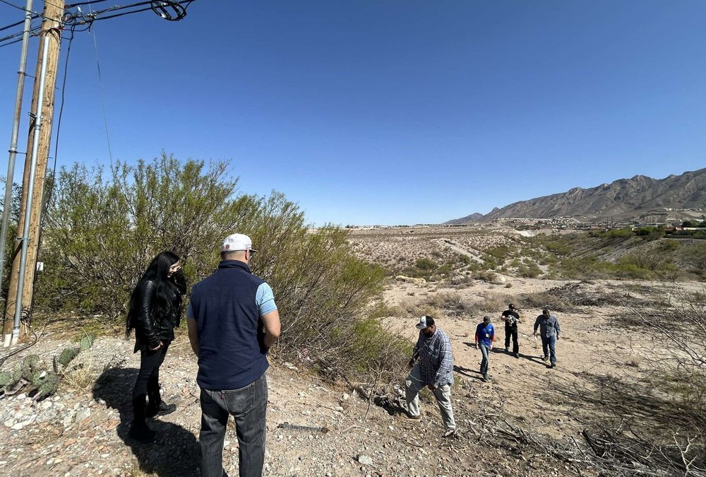 NMOI outreach workers walking a desert lot below the Franklin Mountains