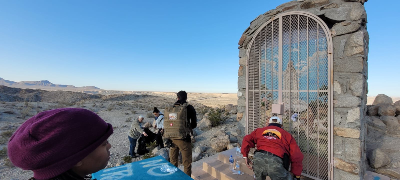 Volunteers cleaning up around a stone shrine overlooking the desert