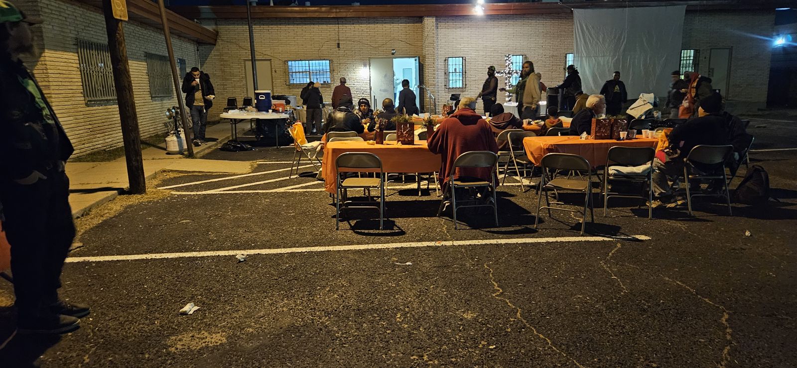 Guests sharing a meal at long tables in a lit parking lot