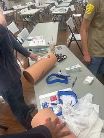 Trainees practicing wound packing and tourniquets at a table