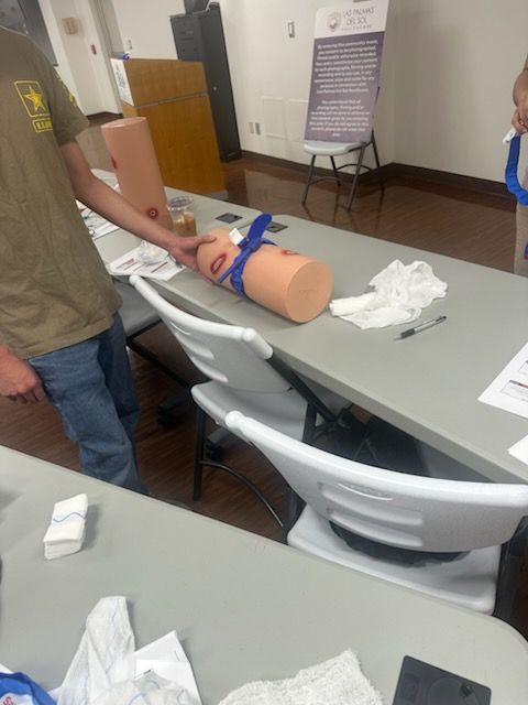 A trainee checking a tourniquet applied to a practice limb